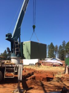 Crain lifting septic tank into ditch