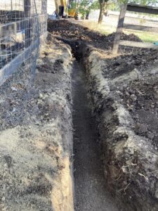 Digging a utility trench in narrow yard by hand with shovel